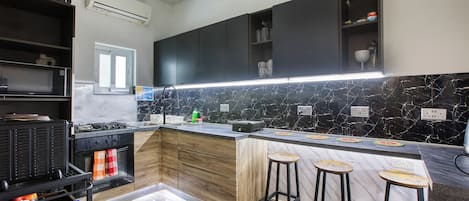A modern kitchen with a black countertop, wooden cabinets, and a marble backsplash.
