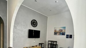 Uma sala de estar moderna com um amplo arco, uma TV de tela plana na parede, um sofá, uma mesinha e um tapete decorativo.