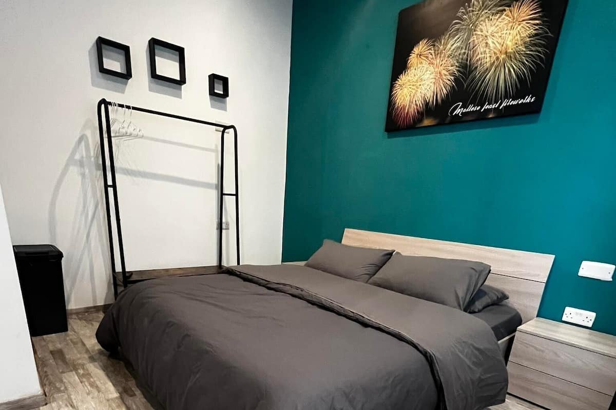 A modern bedroom with a bed, a nightstand, a wall-mounted shelf, and a framed picture of fireworks.