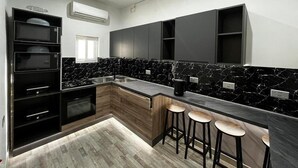 Uma cozinha moderna com armários pretos, bancada de mármore e forno embutido.