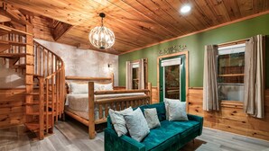 Interior de una cabaña de madera con una escalera espiral, un sofá verde y una cama de madera.