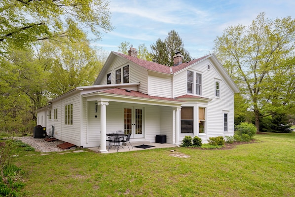 A two-story house with a porch, a covered patio, and a small garden area.