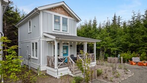 A two-story house with a porch, a blue door, and a small garden area. - Seabrook Robins Nest | Pet Friendly, Hot Tub | 2BR, Sleeps 5, A/C (Pacific Beach)