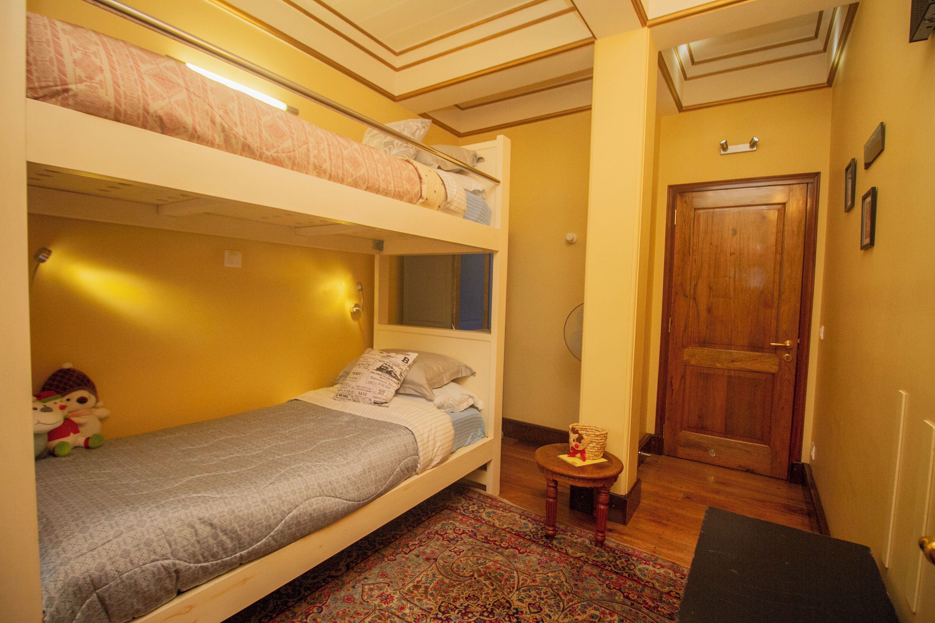 A room with bunk beds, a small round table with a lamp, and a door.