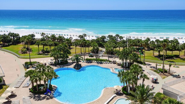 Een resort met een groot zwembad, toegang tot het strand en palmbomen.