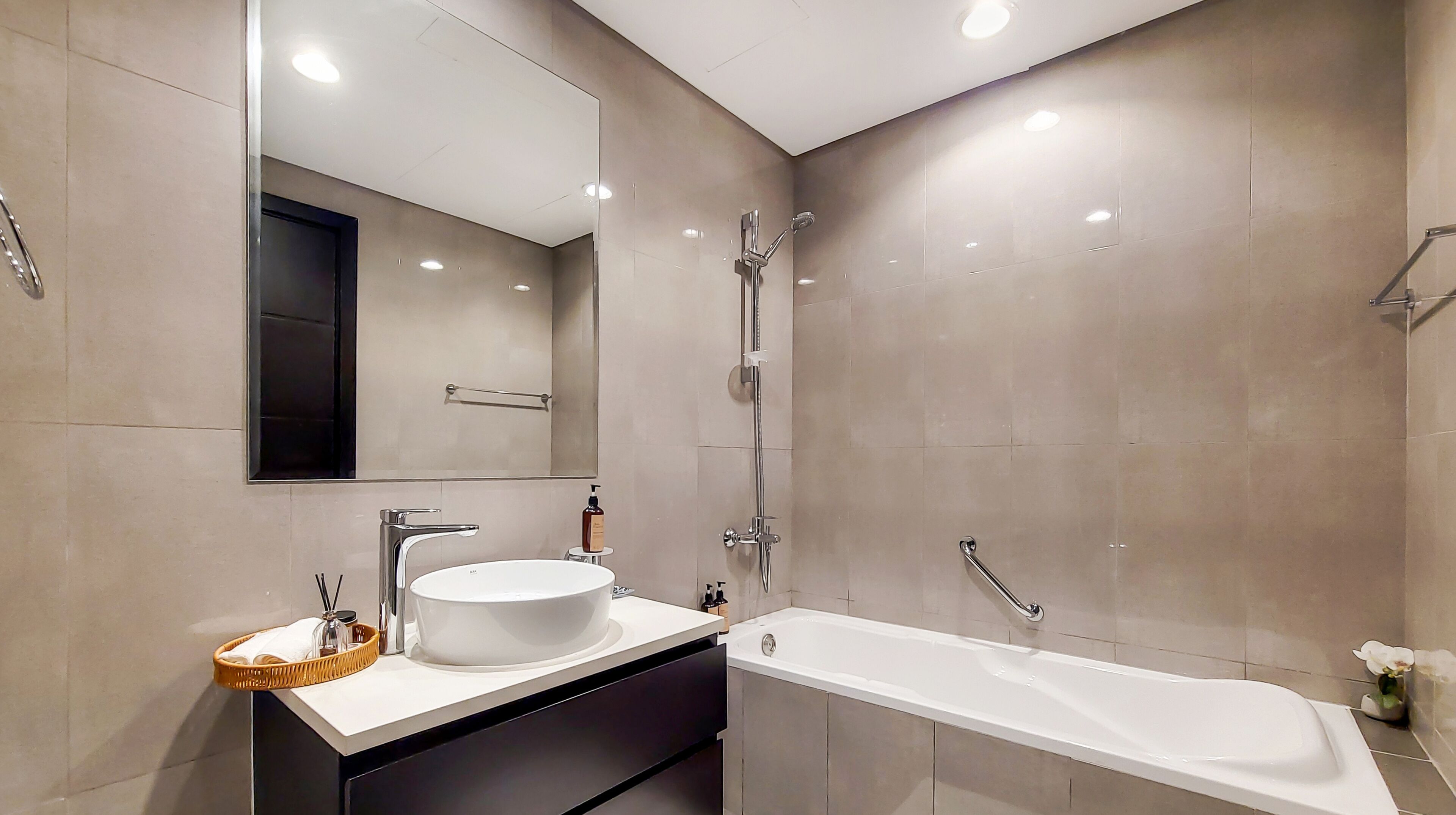 A modern bathroom with a large mirror, a round sink, a bathtub, and a shower.