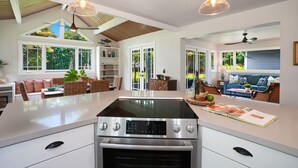 Una cocina amplia con una isla central, horno empotrado e iluminación colgante.