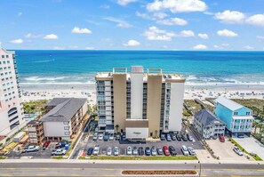 Ein Hotel mit Parkplatz, Blick auf den Strand und den Ozean.