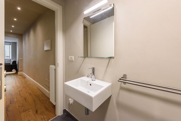 Une salle de bain avec un lavabo blanc, un miroir et un radiateur.