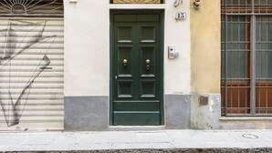 A green door with two round knockers, a metal gate to the left, and a window with metal bars to the right. - Dimora Santa Croce by Mmega (Florence)
