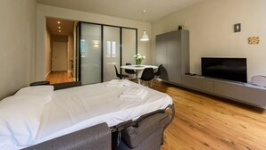 A modern bedroom with a bed, a TV, a desk, and a dining area. - Dimora Santa Croce by Mmega (Florence)