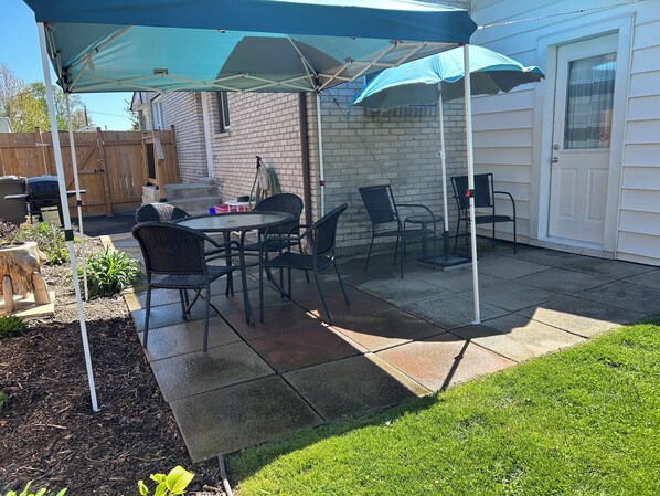 A patio with a covered seating area, a grill, and a brick wall. - Pearl on Pearl in Downtown Kingsville! (Kingsville)