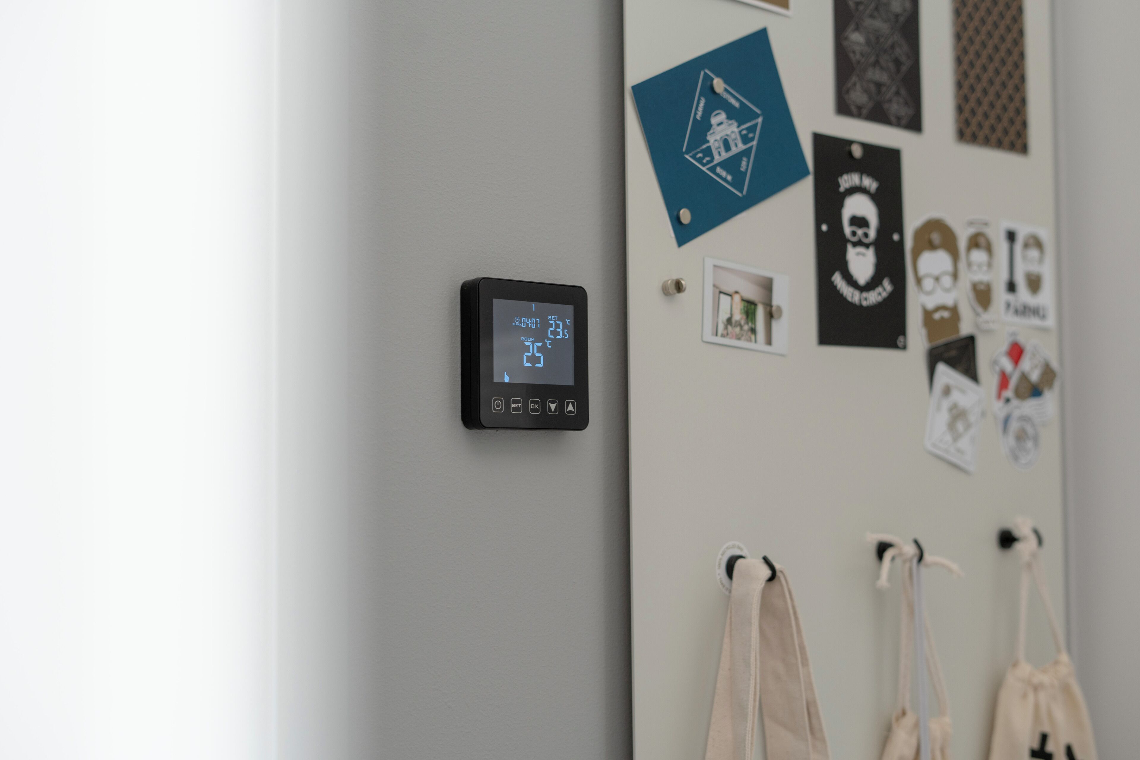 A thermostat on a wall, a door with a towel rack, and various wall decorations.