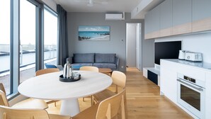 A modern kitchen with a built-in oven, a dining area with a round table and chairs, and a large window overlooking a body of water. - Bob W Pärnu (Parnu)