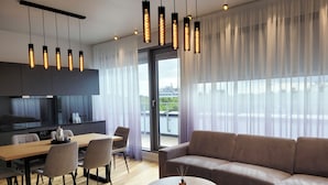 A modern living room with a sofa, dining table, chairs, and a kitchen area with a TV. - Bob W Pärnu (Parnu)