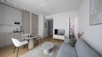 A modern living room with a grey sofa, a round coffee table, and a dining area with a small table and chairs.