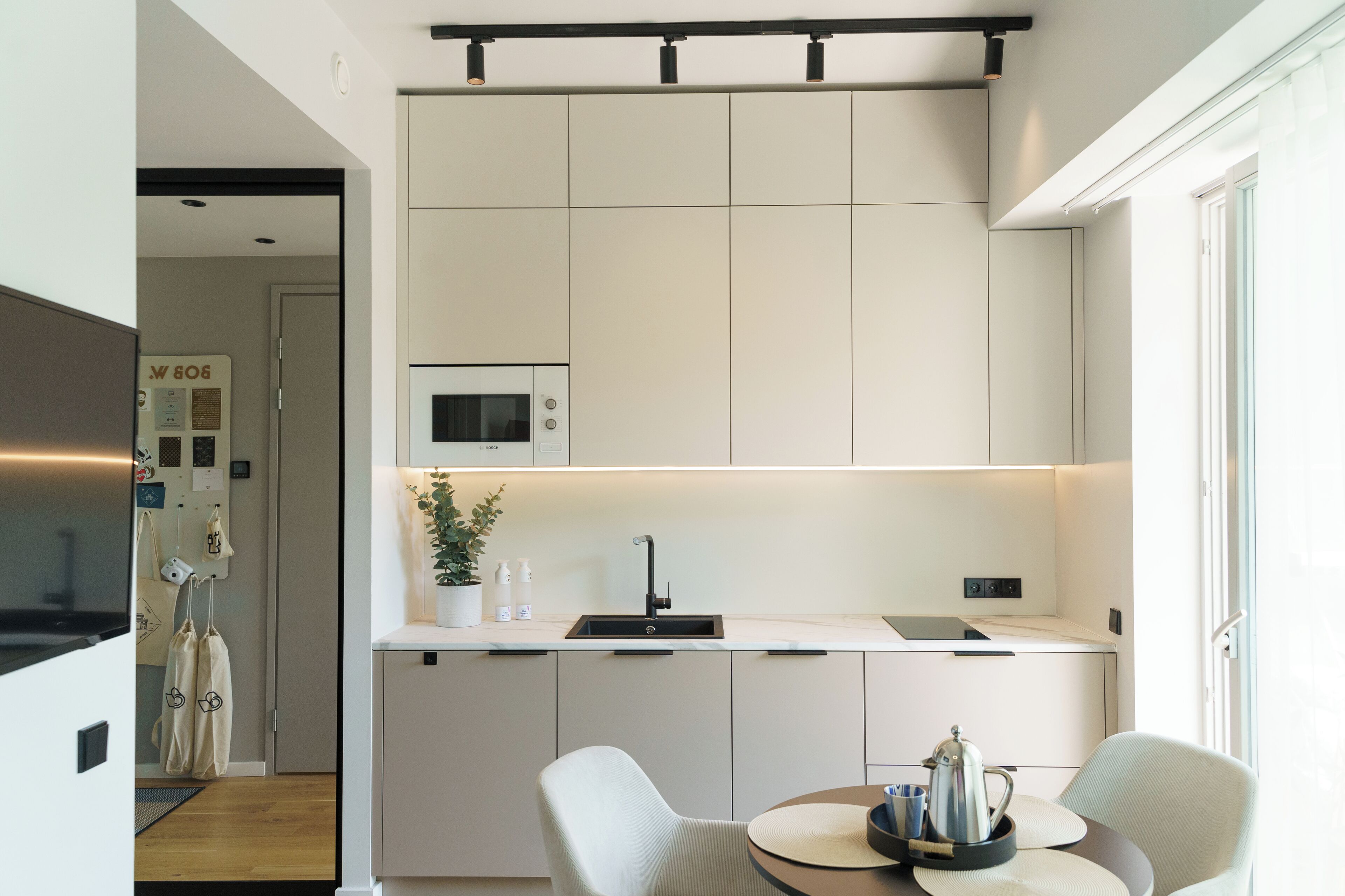 Una cocina moderna con microondas, pileta y comedor con sillas y una mesa.