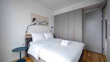 Een moderne slaapkamer met een groot bed, een nachtkastje, een lamp en een kledingkast.