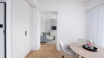 Un salón moderno y minimalista con comedor, que presenta suelo de madera, paredes blancas y muebles contemporáneos.