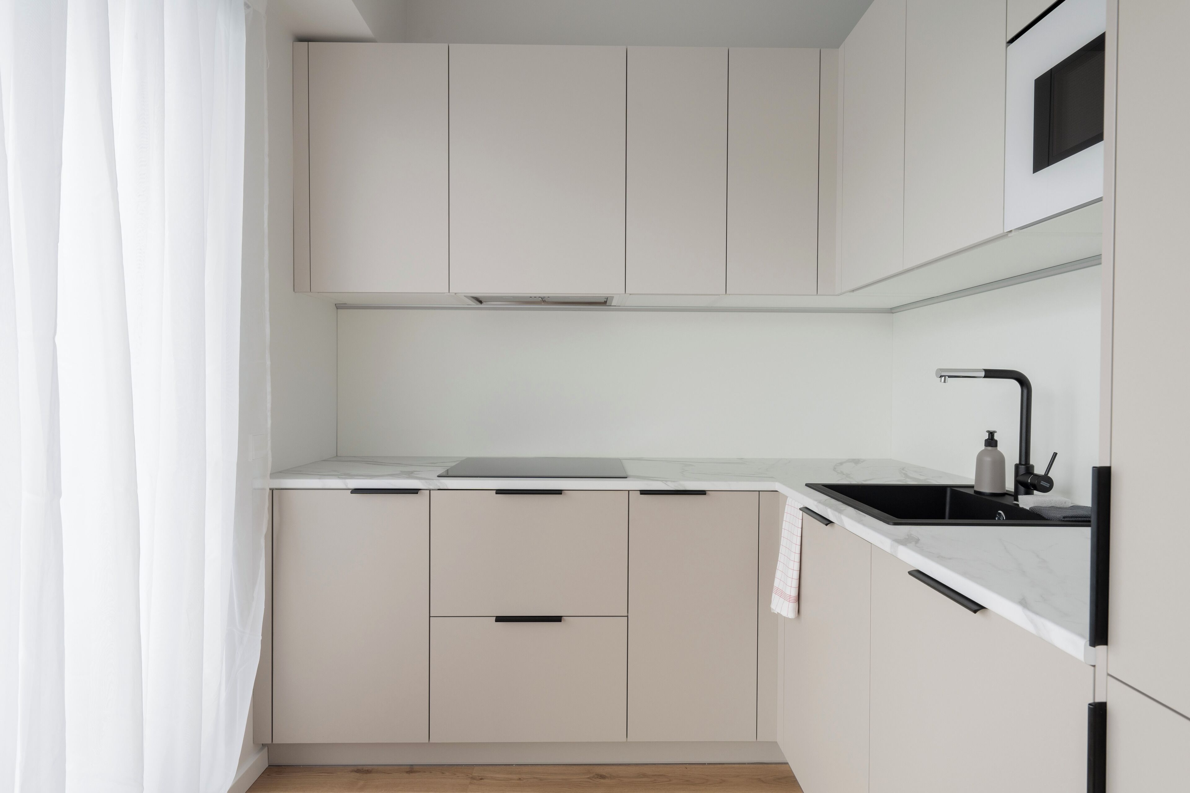 A modern kitchen with white cabinets, a black countertop, and a sink with a faucet.