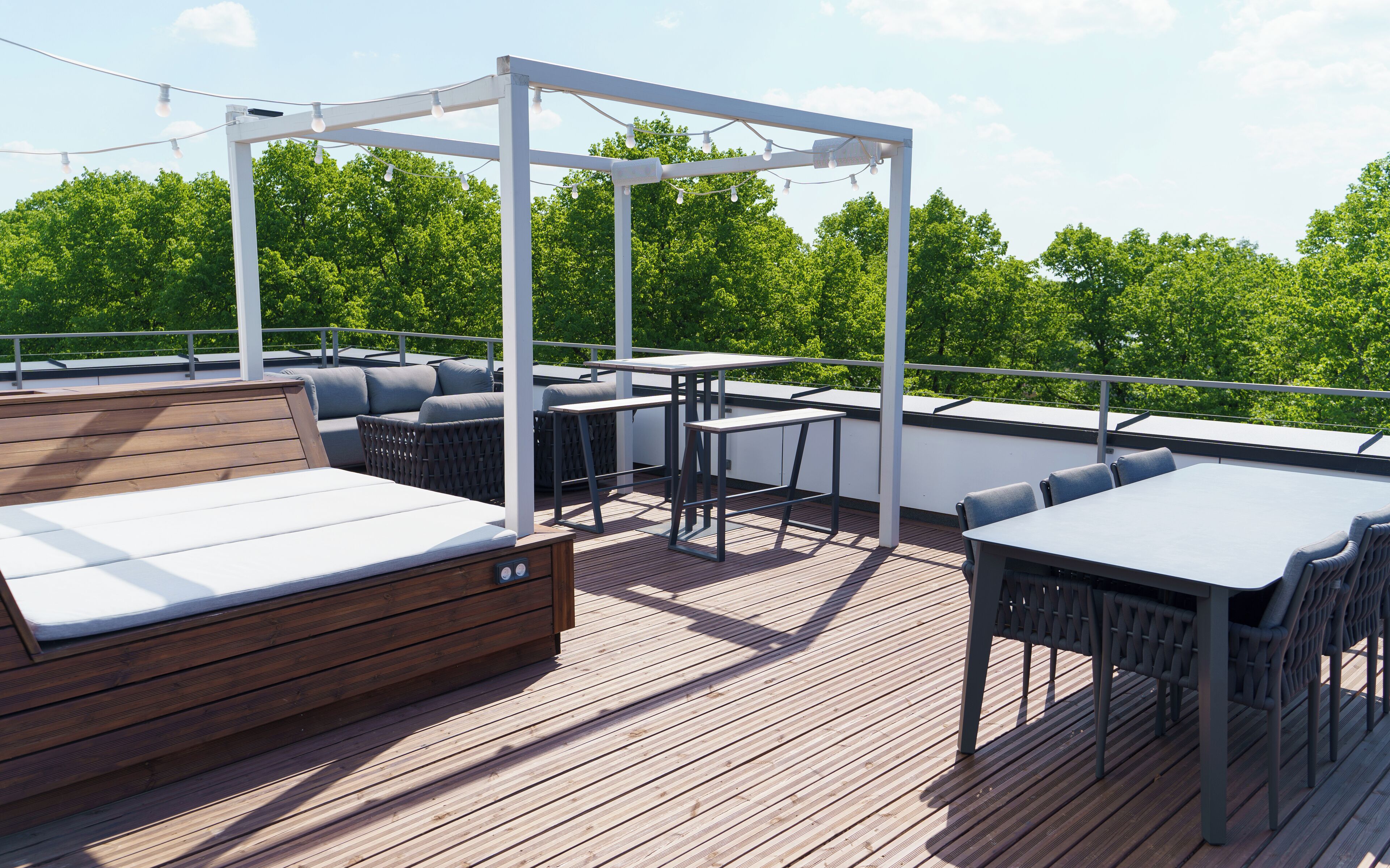 A wooden deck with outdoor seating, including a sofa and tables, under a white pergola.