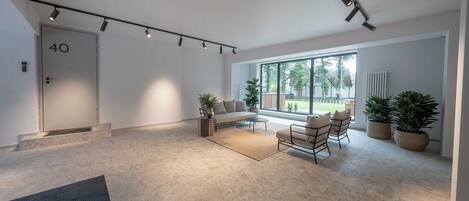 A spacious living area with a sofa, chairs, and potted plants.
