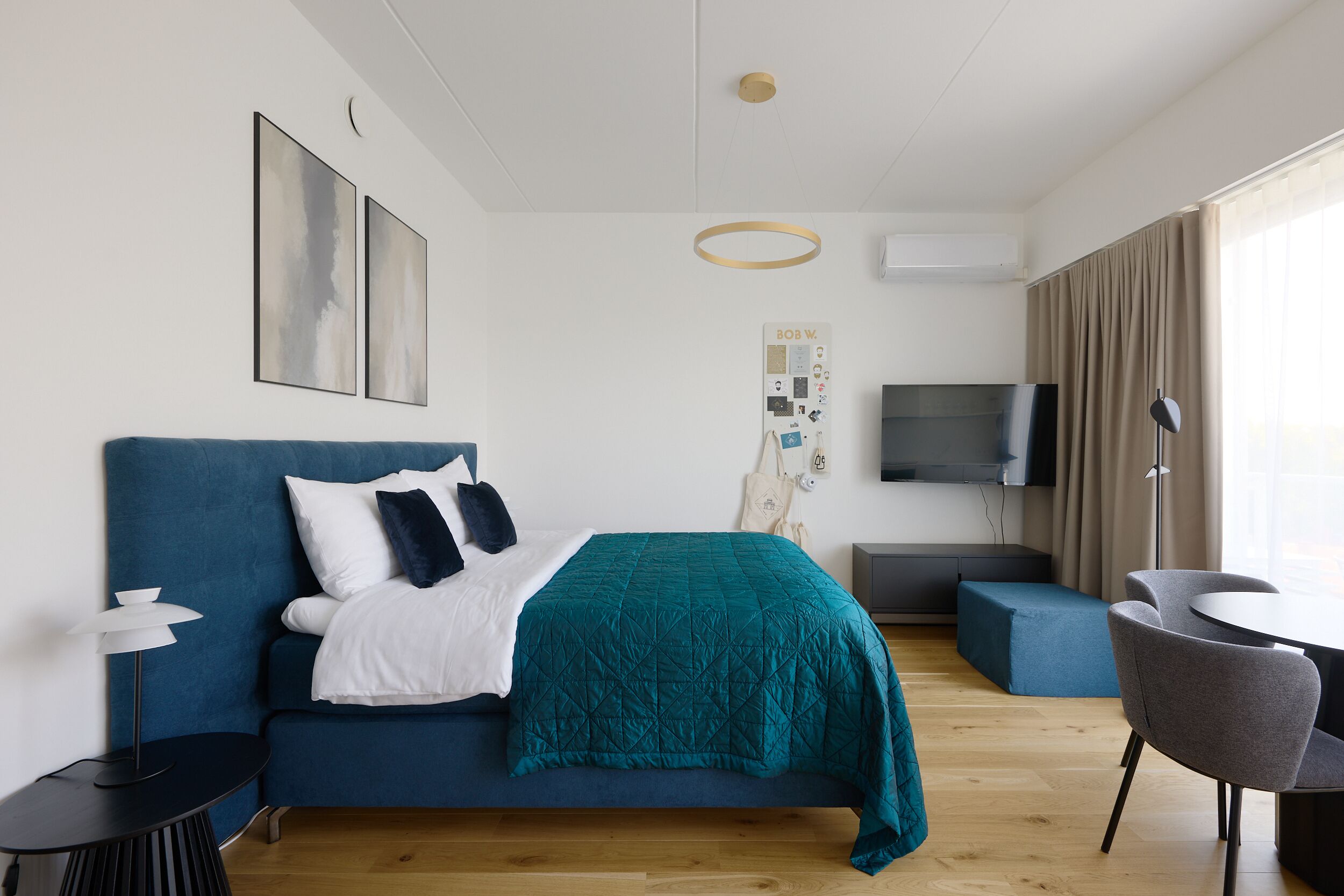 Een moderne hotelkamer met een bed, een televisie, een bureau en een zithoek.