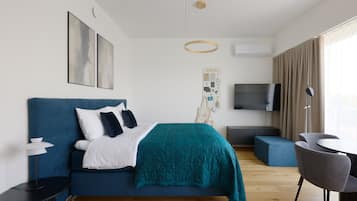 Een moderne hotelkamer met een bed, een televisie, een bureau en een zithoek.