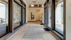 A spacious hallway with large windows, a wooden floor, and a central chandelier. - SABL14 - Stunning Caldera Springs, Gourmet Kitchen, Heated Patio, New Hot Tub (Sunriver)