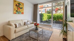 Un salon moderne avec un canapé beige, une table basse et un tableau abstrait aux couleurs vives accroché au mur.