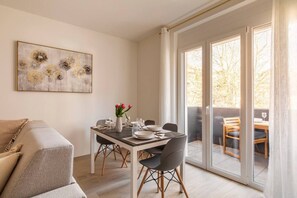 A dining area with a table set for two, a sofa, and a sliding glass door leading to an outdoor seating area. - Romantic luxury apartment with private parking (Lugano)