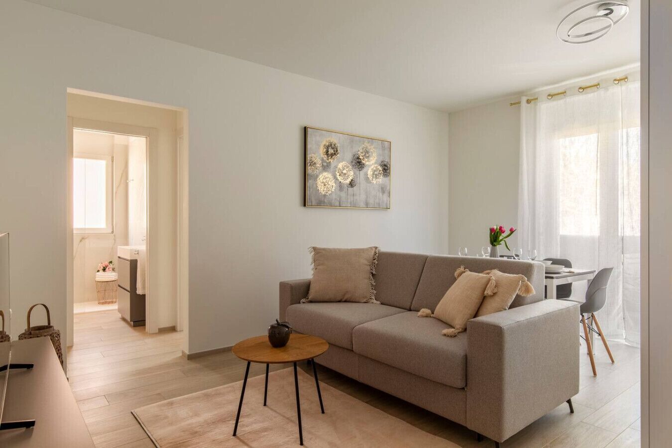 A modern living room with a sofa, a coffee table, and a dining area with a table and chairs.
