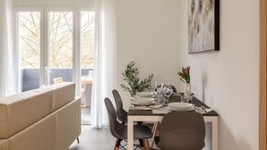 Un coin repas avec une table dressée pour quatre personnes, des chaises, un vase rempli de fleurs et un tableau accroché au mur.