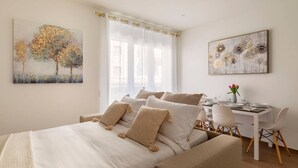 Une chambre avec un lit, un bureau et des chaises. Les murs sont ornés de tableaux.