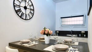 Een moderne eethoek met een donkere tafel, witte stoelen en een grote wandklok.