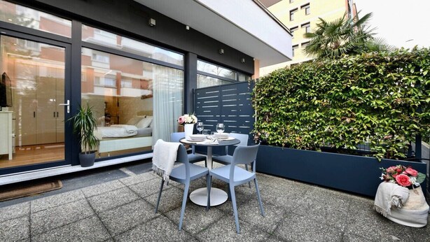 Een modern buitgedeelte met een tafel, stoelen, een bloempot en een decoratieve vaas met bloemen.
