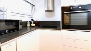 Een moderne keuken met een magnetron, waterkoker en oven.