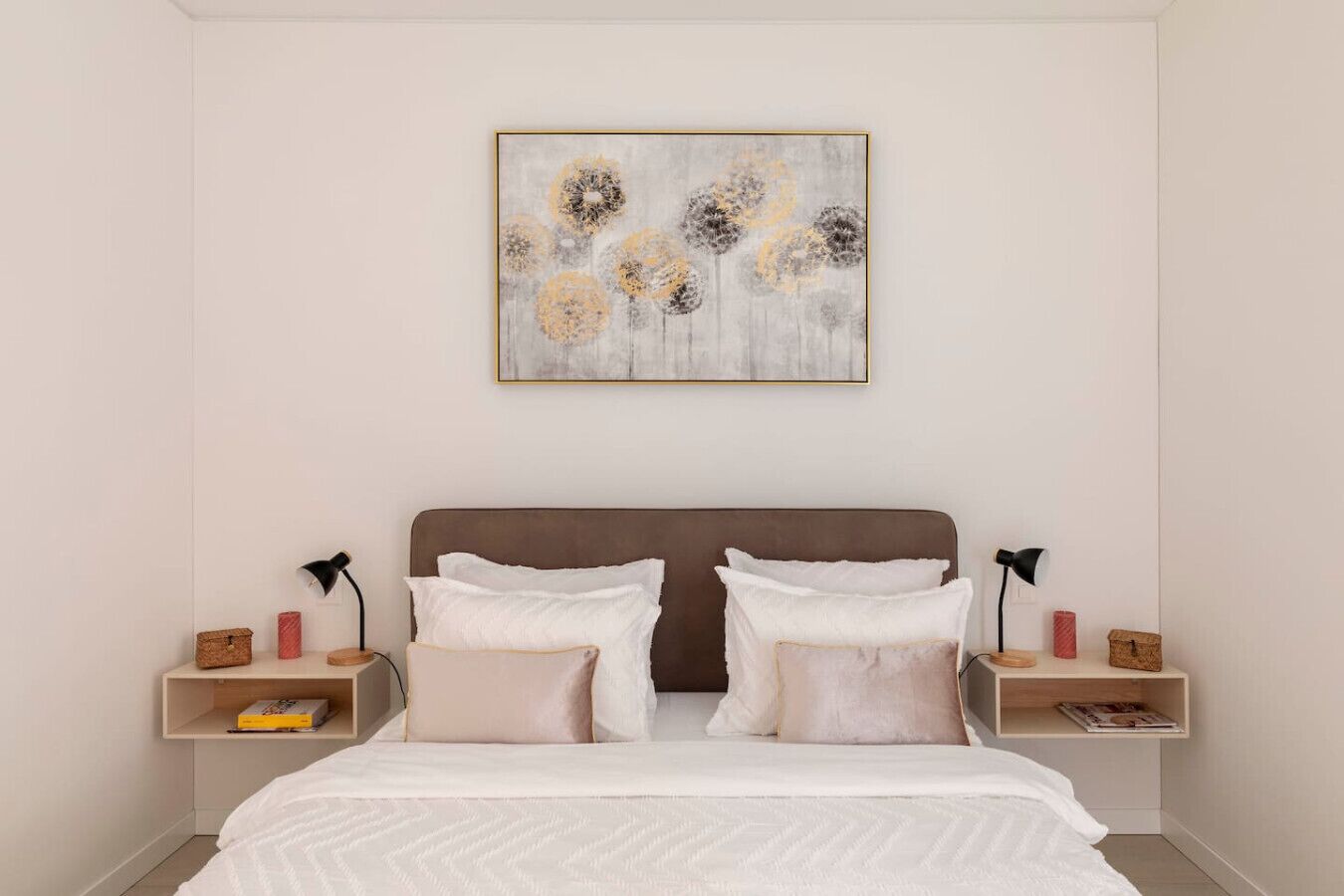 Ein Schlafzimmer mit einem Bett, zwei Nachttischen, einem Wandbild und einem Bücherregal.