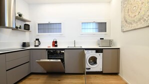 A compact kitchen with a dishwasher, washing machine, and a microwave on the countertop. - Blue Diamond - Gorgeous lakefront apartment with parking (Lugano)
