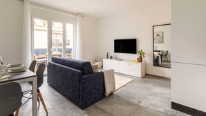 Ein modernes Wohnzimmer mit Sofa, Esstisch und Fernseher.