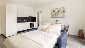Ein modernes Schlafzimmer mit einem großen Bett, einer kleinen Küchenzeile und einem Essbereich.