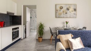 Eine moderne Küche mit einem roten Toaster, ein Essbereich mit einem blauen Sofa und ein Badezimmer mit Marmor.
