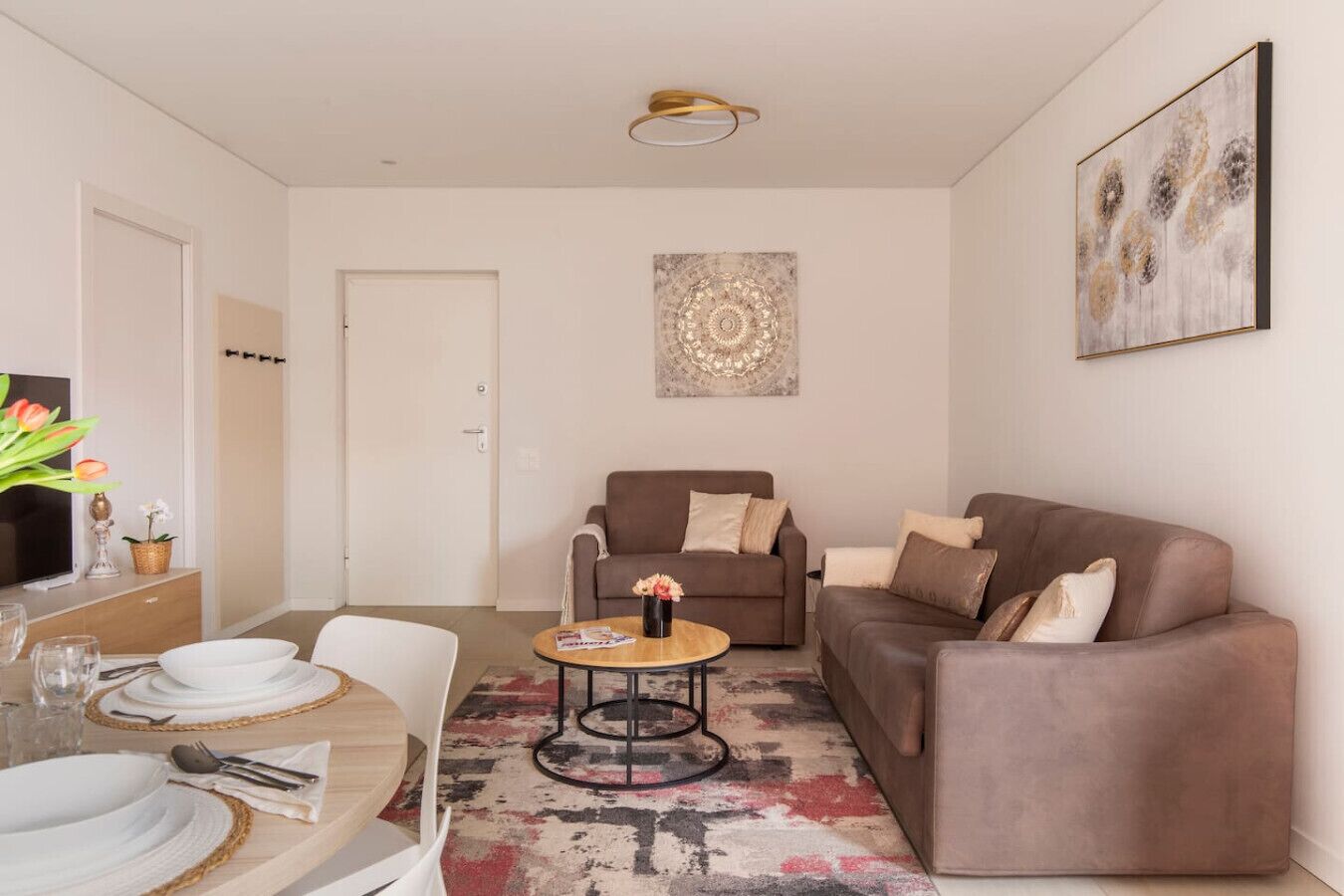A modern living room with a brown sofa, a round coffee table, and a dining area with a white table set.