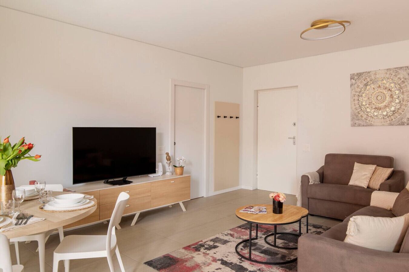 Un salon moderne avec un téléviseur à écran plat, une table à manger pour deux personnes, un canapé et une table basse.