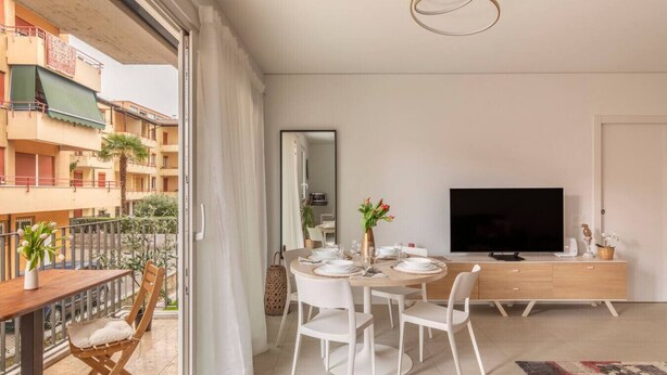 Eine moderne Wohnung mit Essbereich, Fernseher und Balkon mit Pflanzen.