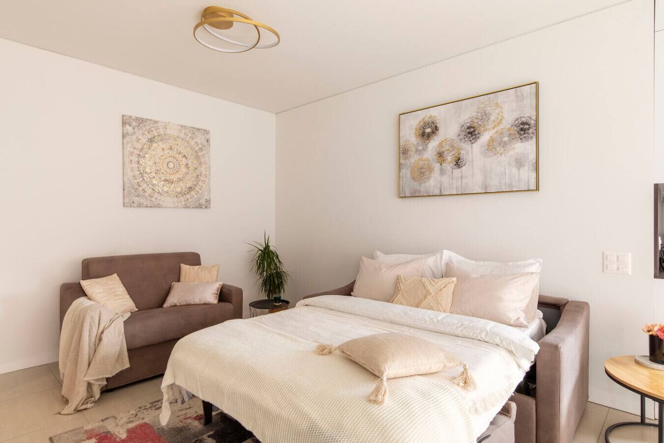 Ein modernes Schlafzimmer mit einem großen Bett, einer Couch und zwei Wandbildern.