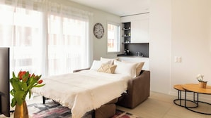 A modern bedroom with a bed, bedside table, and a small round table with a plant. - LUNA LUX - Elegant and central apartment with parking space (Lugano)