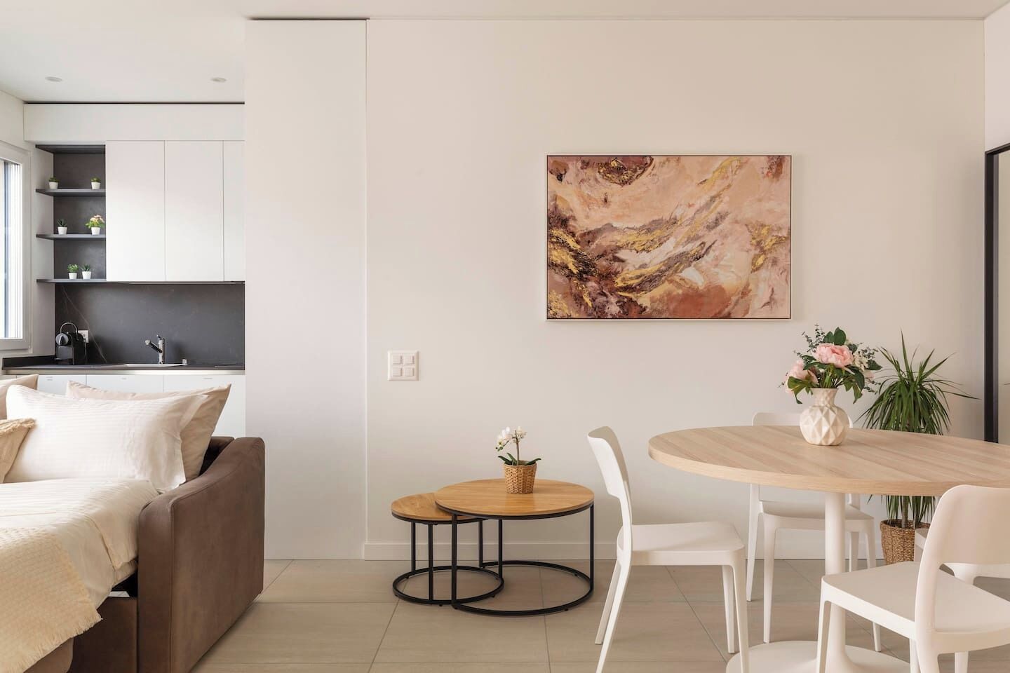 Uma sala de estar moderna com sofá, mesa de jantar com cadeiras e área de cozinha com prateleiras.
