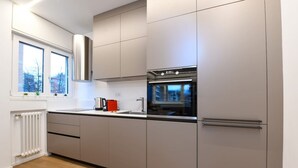 Una cucina moderna con mobili grigi, un forno in acciaio inossidabile e una finestra vista edifici.