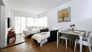 Una camera da letto moderna con un letto, un comodino e un'area pranzo con sedie e tavolo.